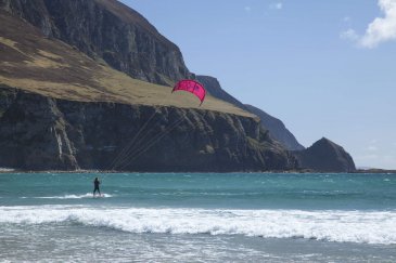 man surfing with cliffs behind